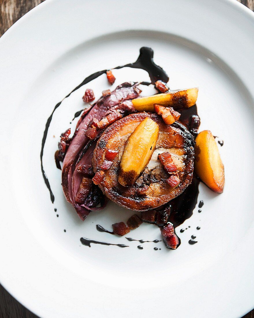 Slice of rolled lamb with fruit slices on white plate