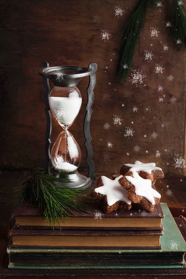 An arrangement featuring an antique sand timer and chocolate and nut Christmas biscuits