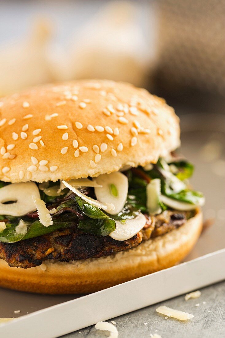 Vegetarischer Burger mit Bohnenbratling, sautiertem Knoblauch-Spinat und Parmesanspänen
