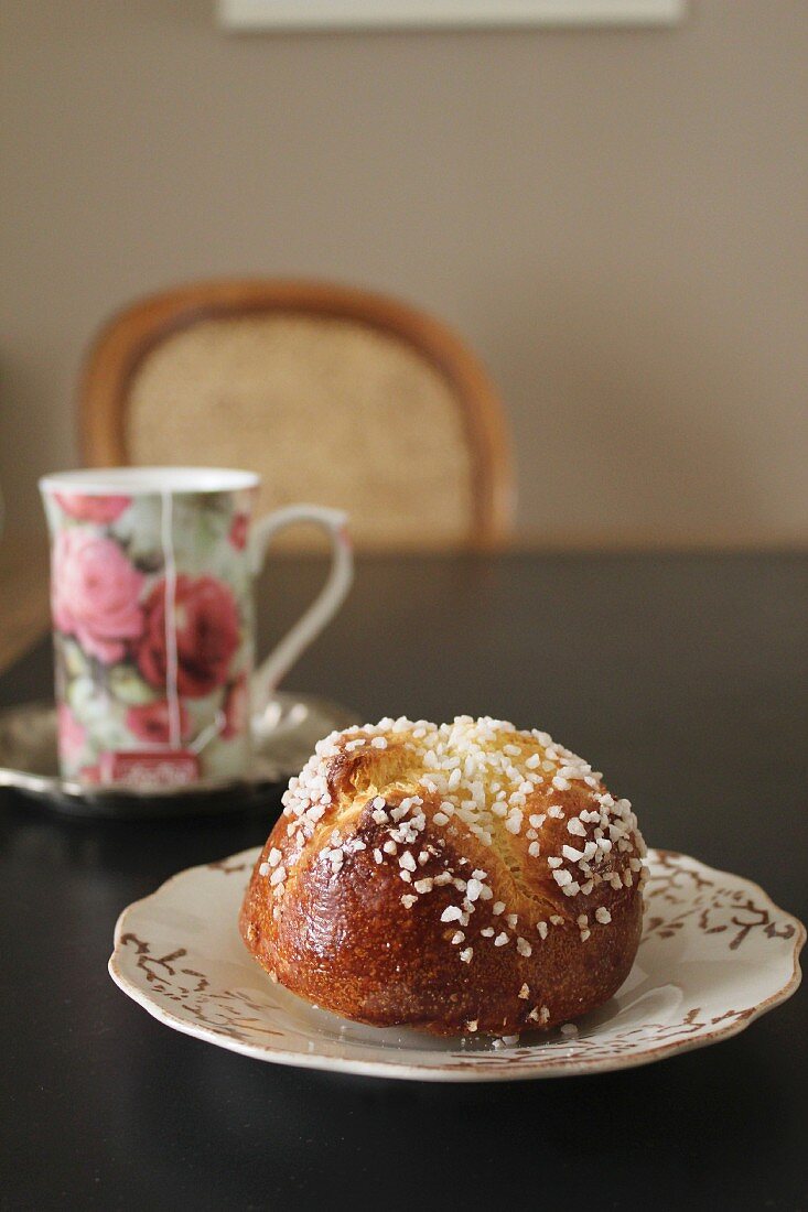 Brioche with sugar nibs and tea in a floral-patterned mug