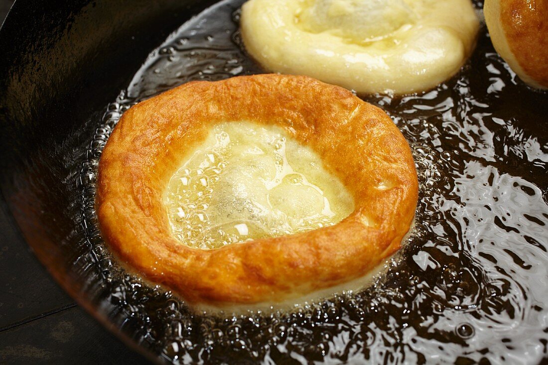 Bauernkrapfen (Austrian yeast dough pastries) being fried in a pan of oil