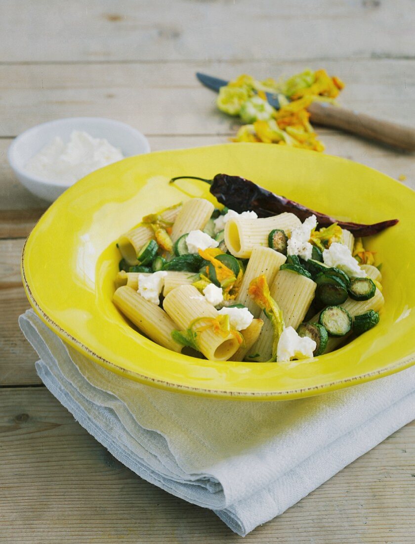 Rigatoni with mini courgettes in a yellow plate