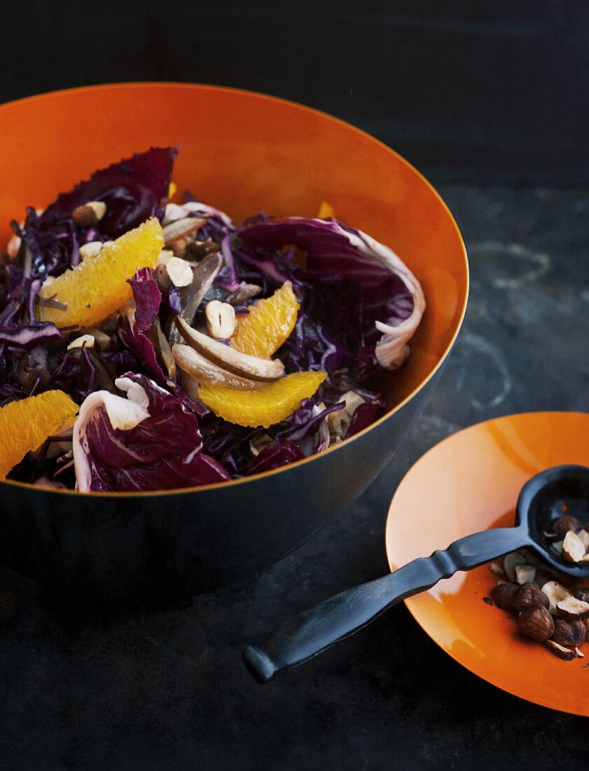 Red cabbage salad with oranges and dates on a dark surface