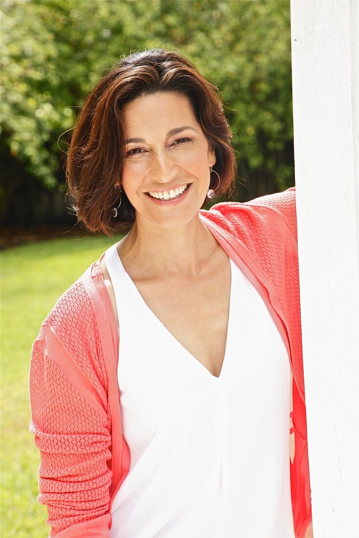 Dark-haired woman wearing top and cardigan in garden