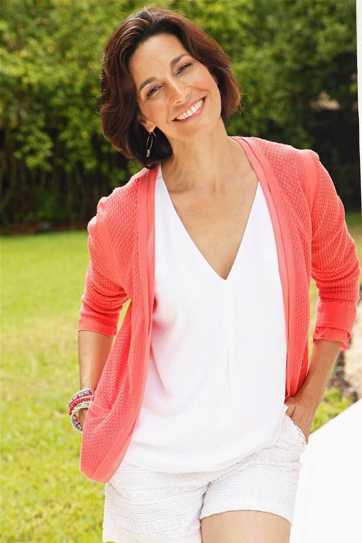 Dark-haired woman wearing top and cardigan in garden