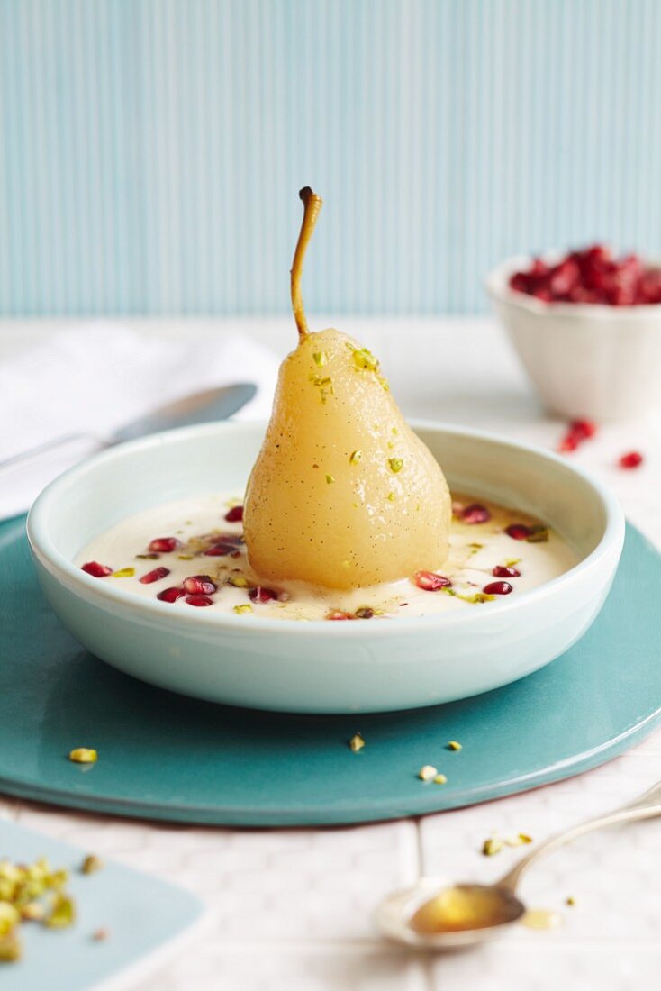 A poached pear in a creamy sauce with pomegranate seeds