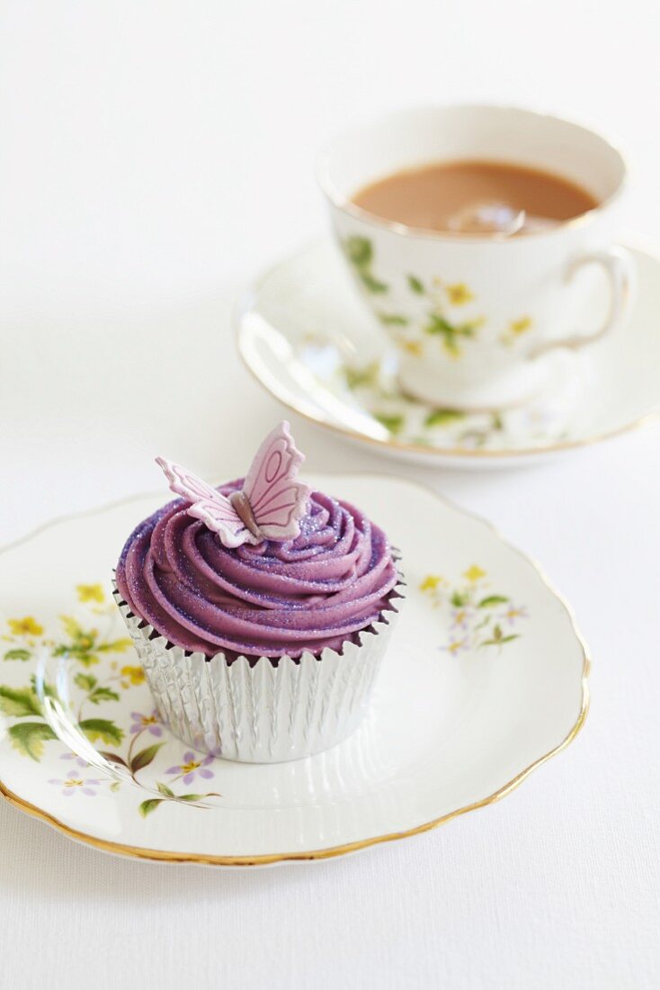 A butterfly cupcake with a cup of tea