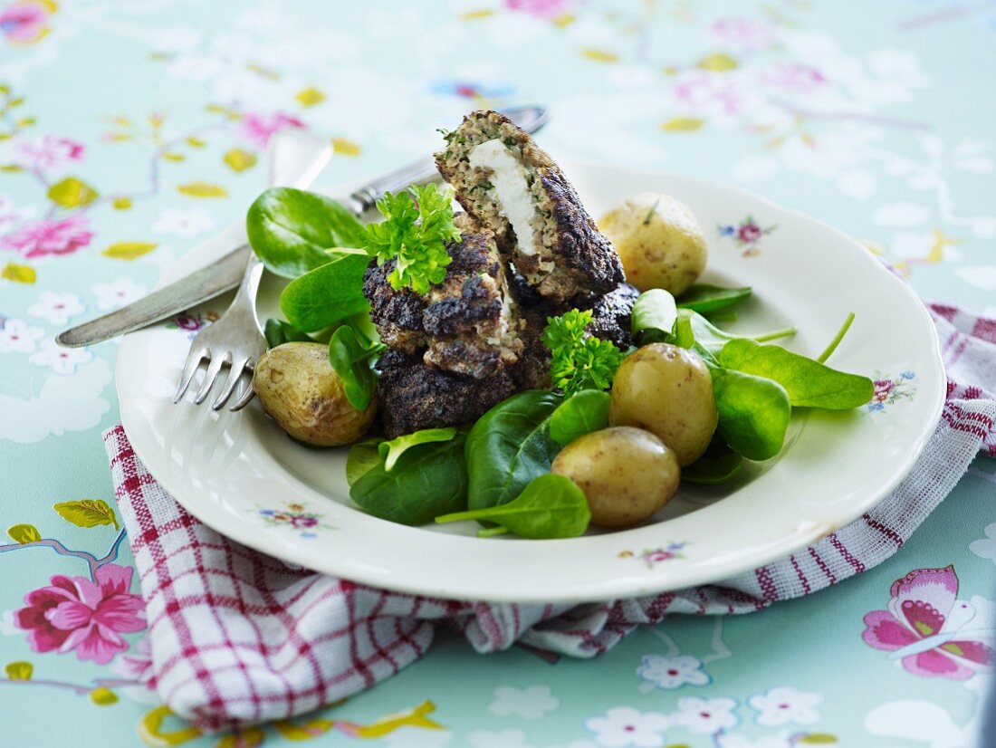 Meatballs filled with feta cheese served with new potatoes and spinach