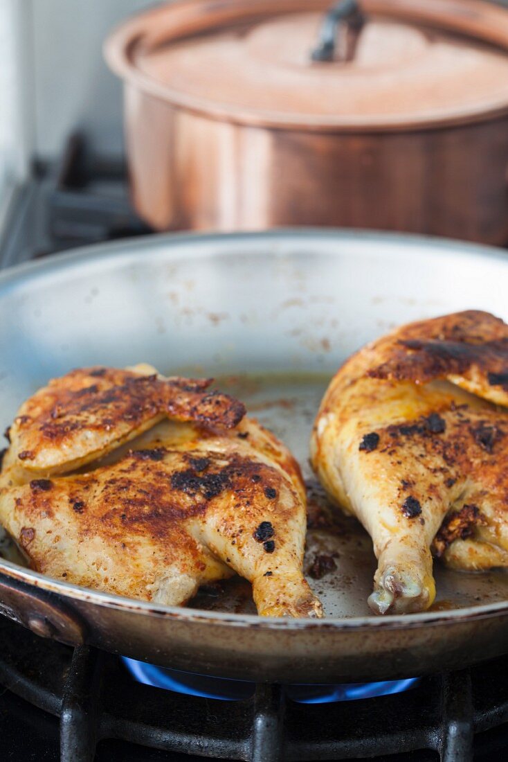 Chicken halves in a pan