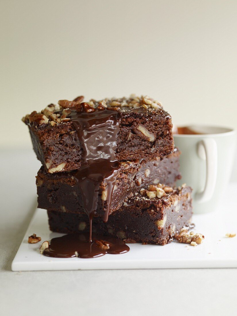 A stack of brownies dripping with chocolate sauce