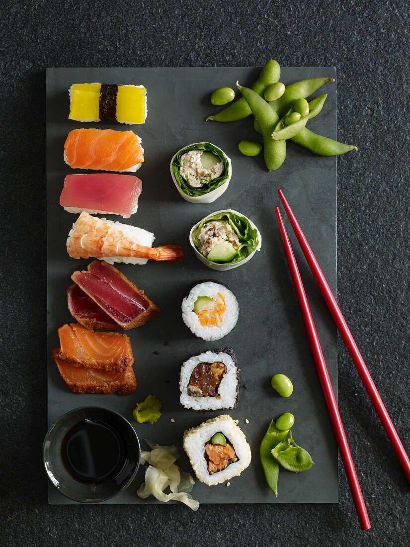 Nigiri-Sushi, California Rolls, Maki-Sushi und Sashimi auf Steinplatte