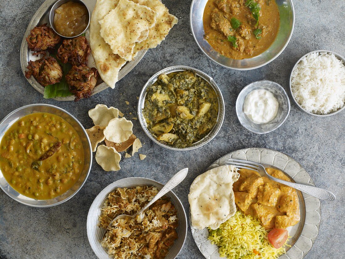 Indisches Buffet mit Naan-Brot, Reis und verschiedenen Gerichten