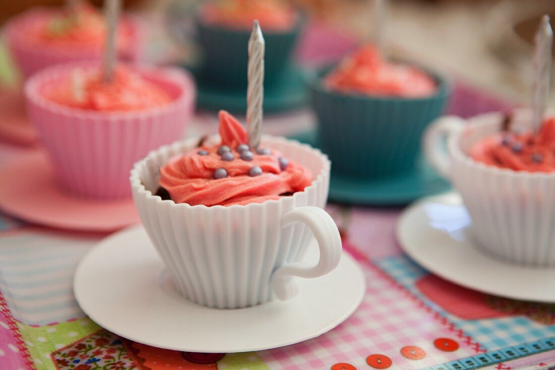 Rosa Cupcakes mit Geburtstagskerzen in Tassen