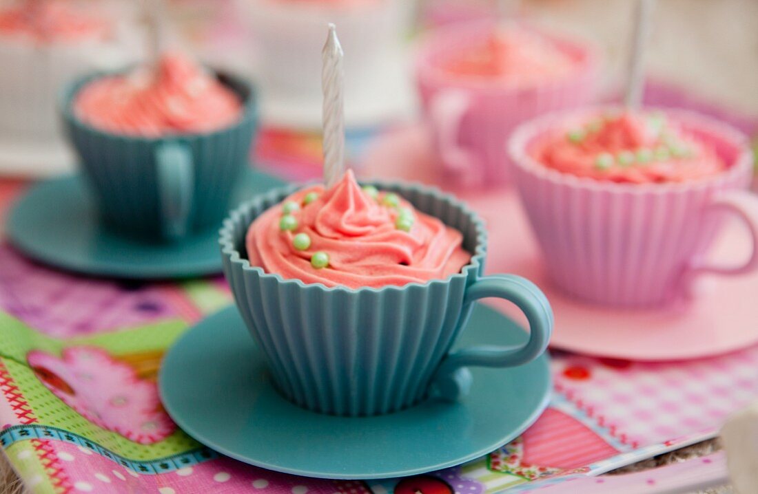 Rosa Cupcakes mit Geburtstagskerzen in Tassen