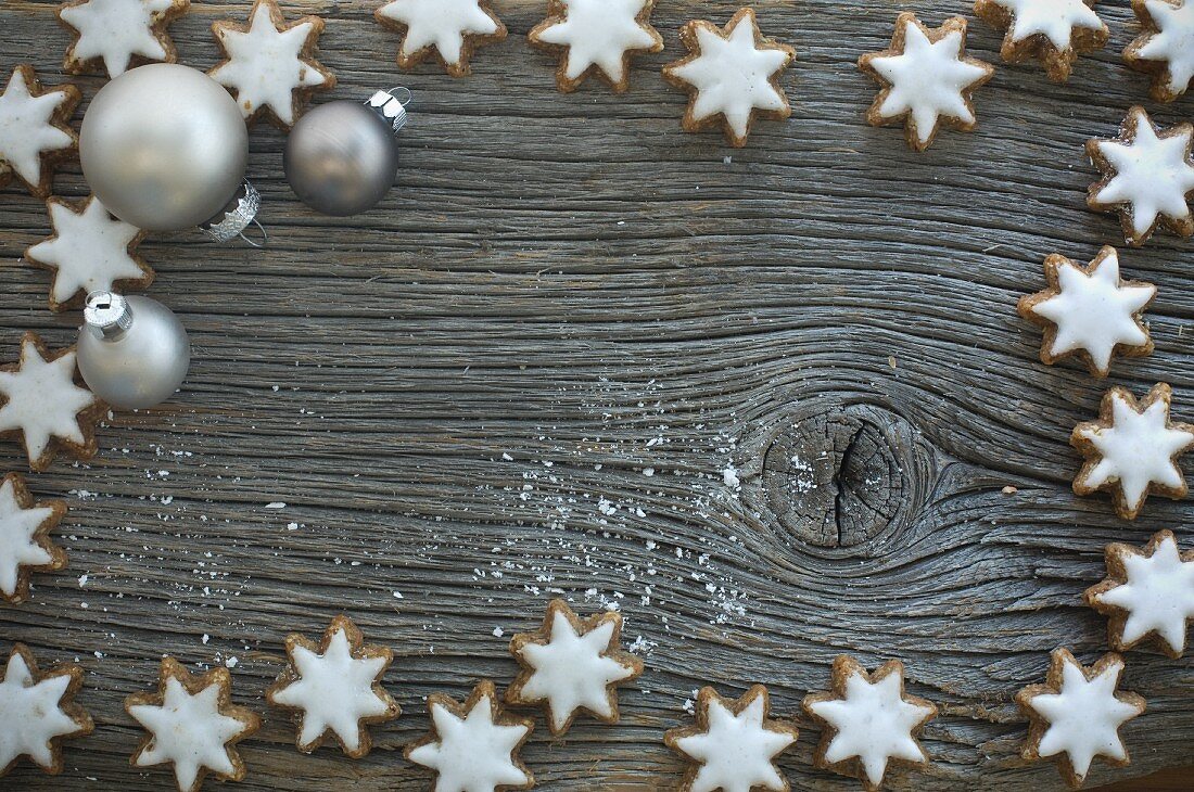 Cinnamon stars and Christmas tree baubles on a rustic wooden board