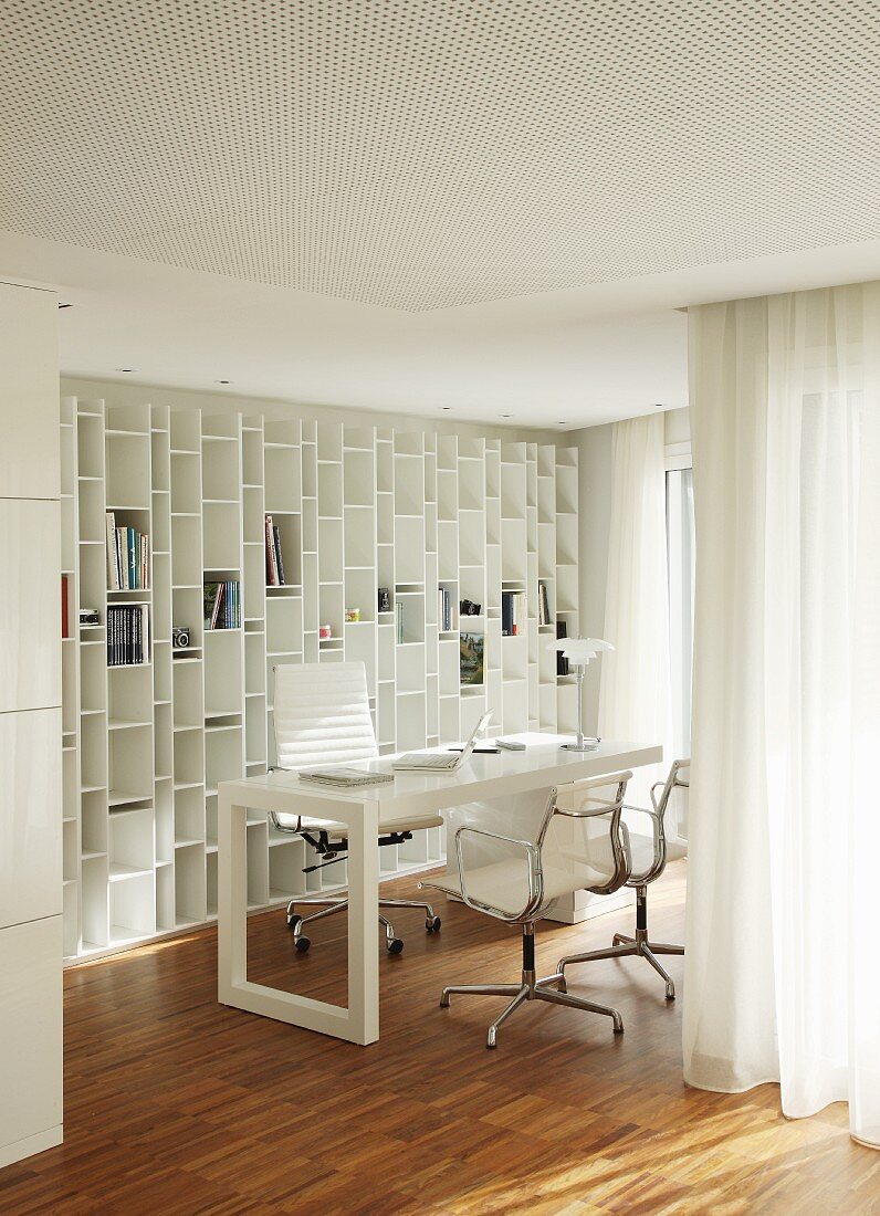 Workspace with Eames Aluminium Chairs and fitted shelving integrated into white interior