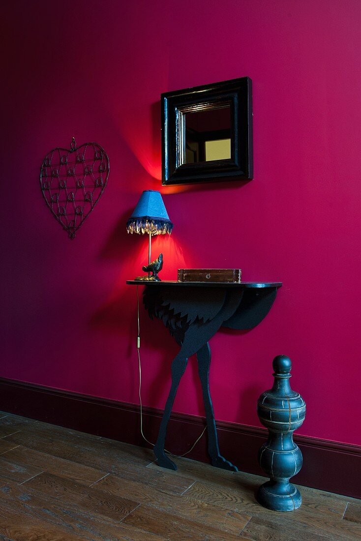 Black console table and mirror on magenta wall