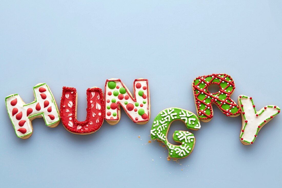 Weihnachtsplätzchen in Buchstabenform bilden das Wort HUNGRY, der Buchstabe G ist angebissen