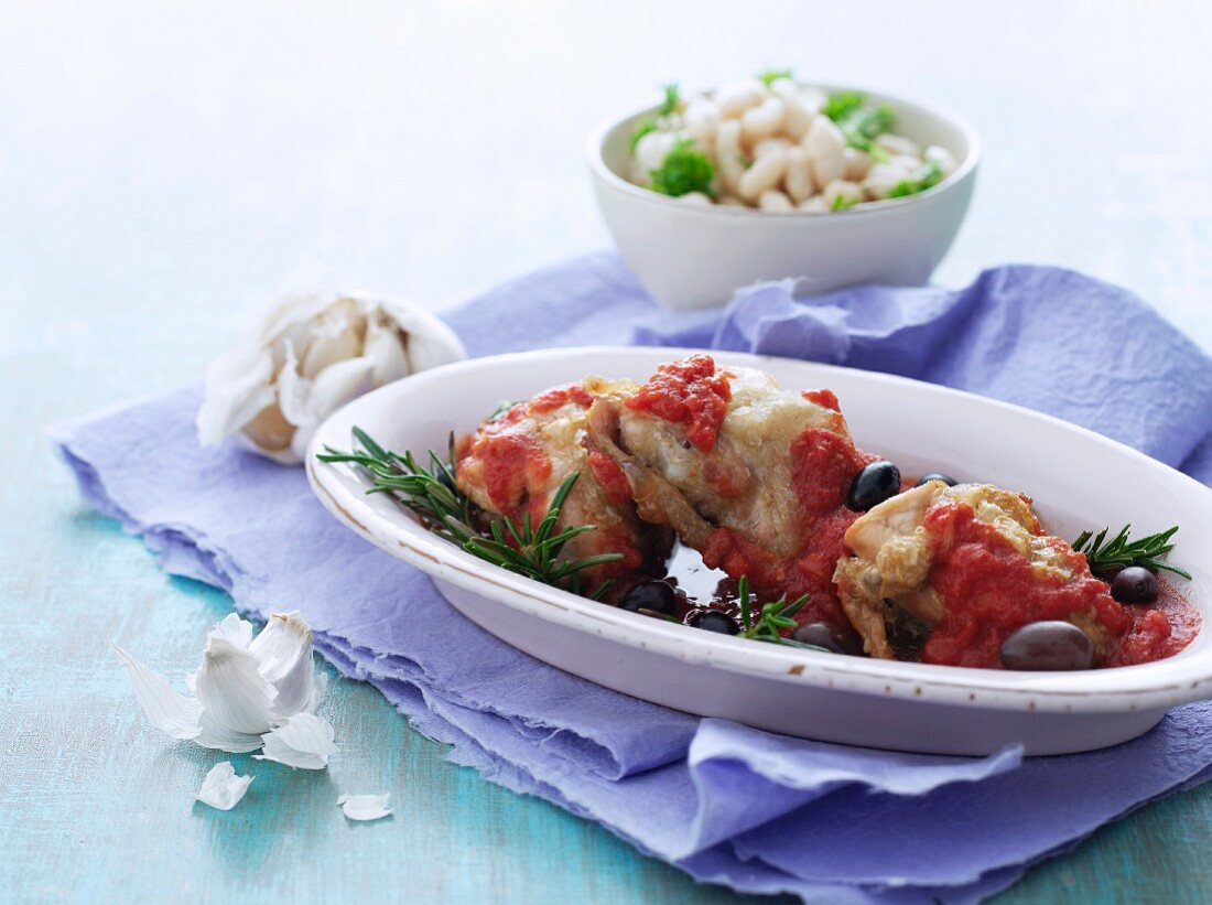 Baked chicken with tomato sauce, olives, rosemary and white beans