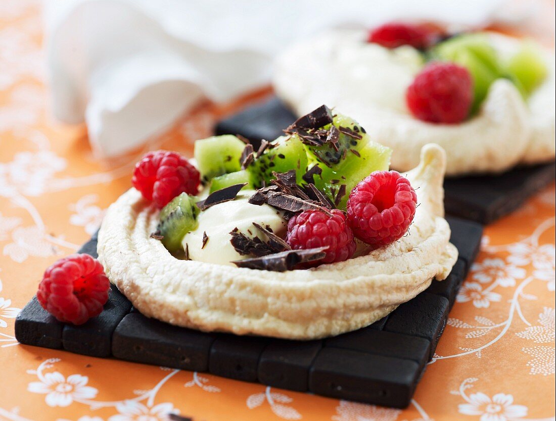 A tartlet with kiwis, raspberries, cream and chocolate curls