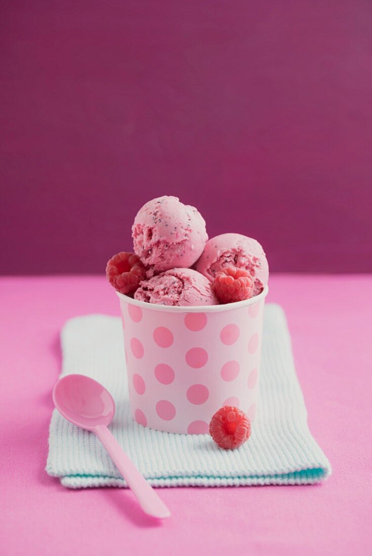 Raspberry ice cream with poppy seeds in an ice cream tub
