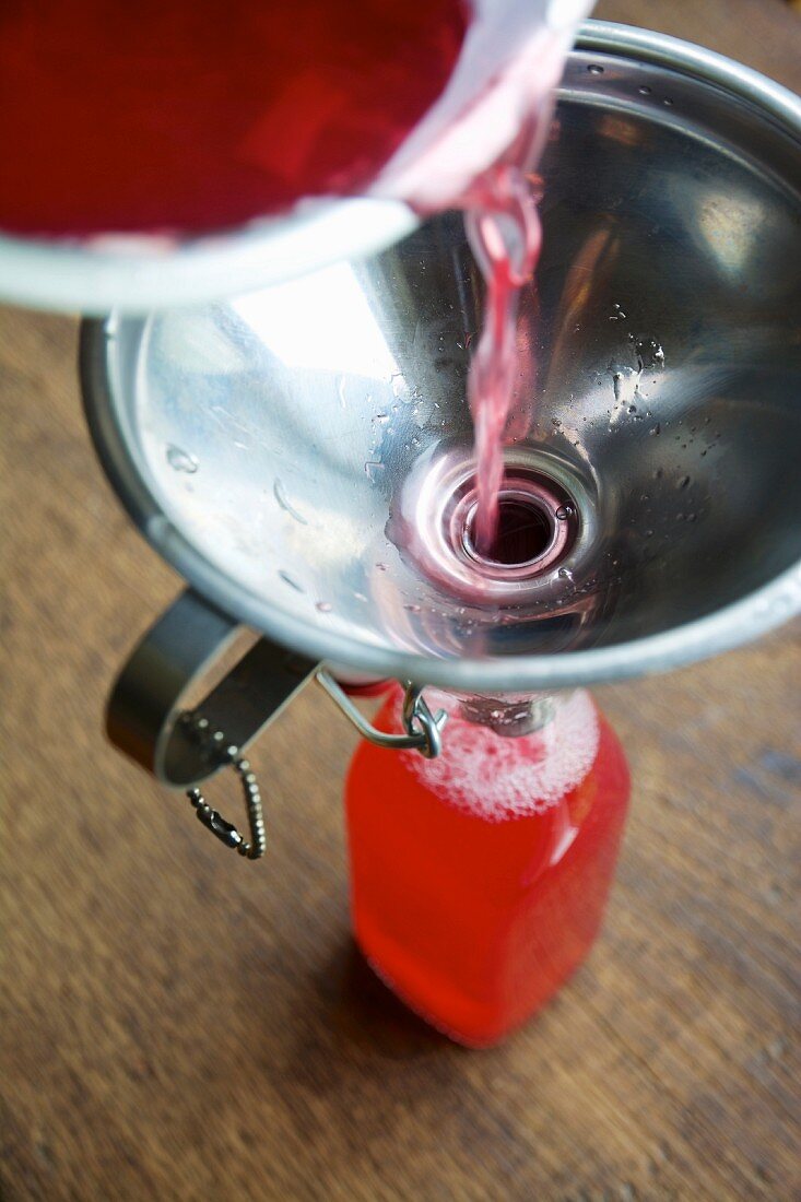 Homemade rhubarb syrup being poured into a bottle