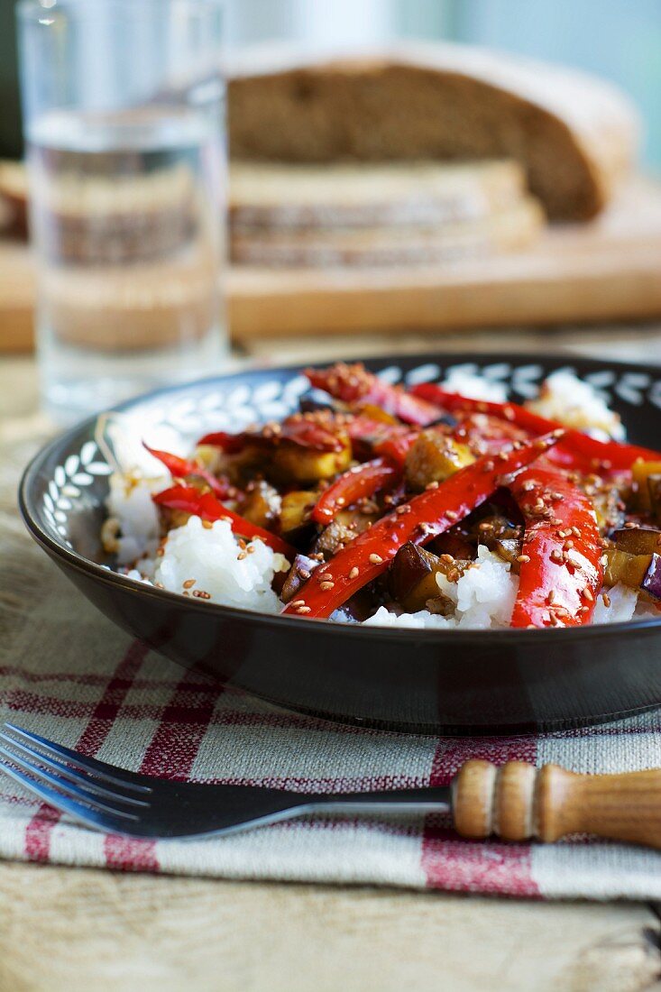 Sweet and sour aubergines with peppers and sesame on a bed of rice