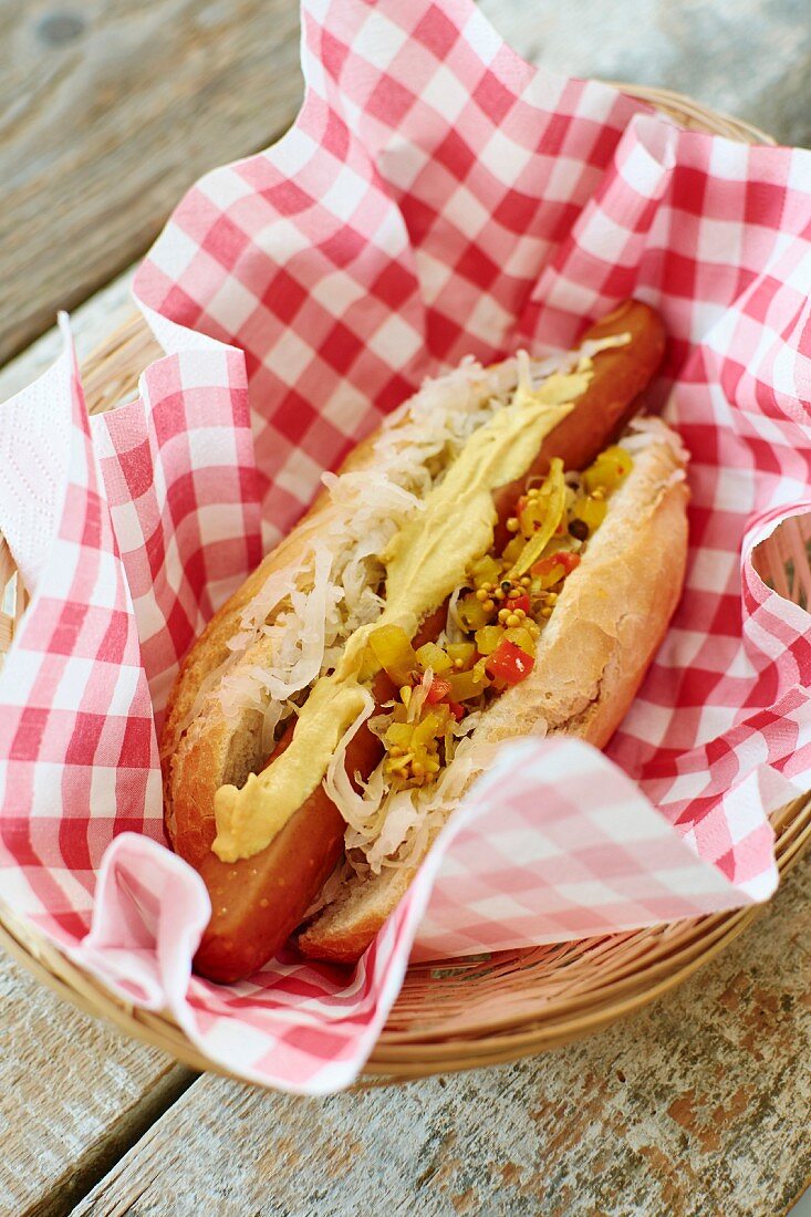 A vegan hot dog with sauerkraut and relish on napkin in a basket