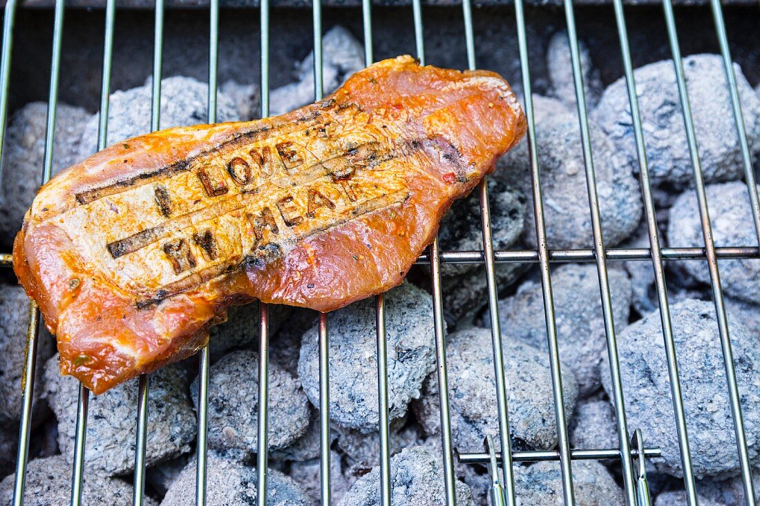 A pork steak with branding on a grill
