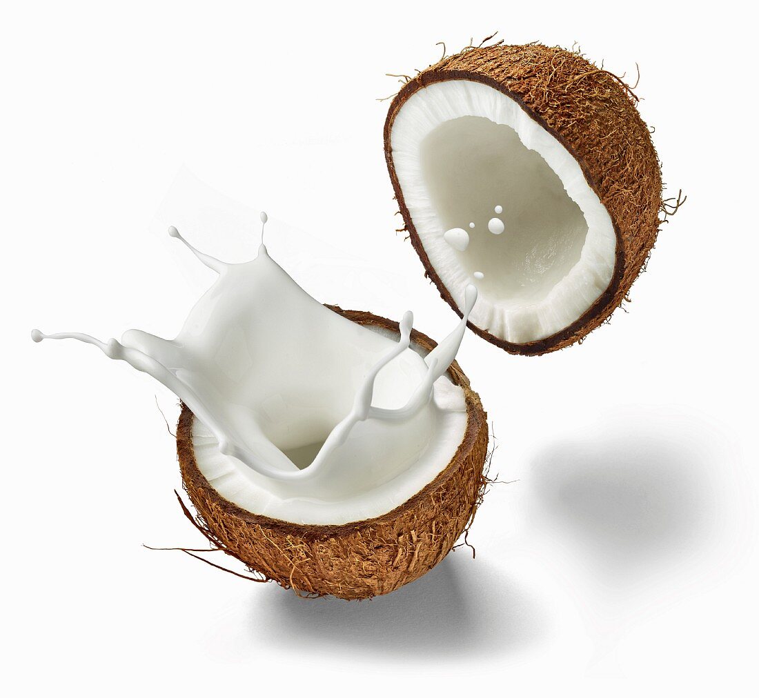 A halved coconut with milk splashing out