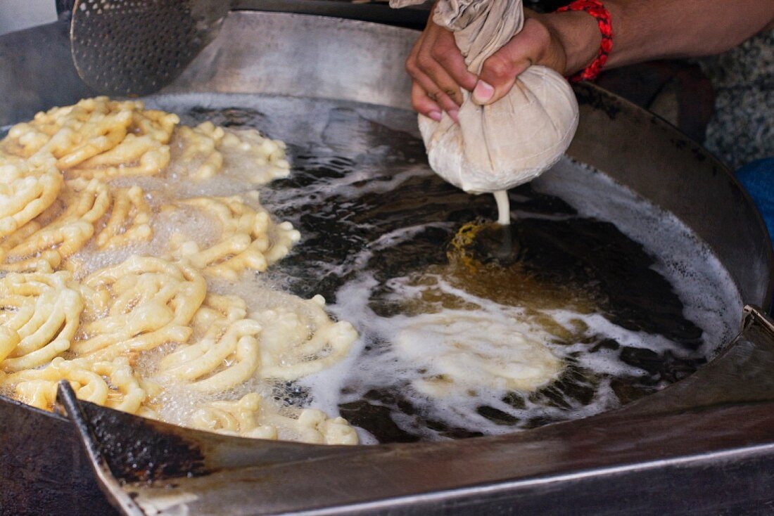 Indische Frau beim Zubereiten von Jalebis (Süsses Spritzgebäck, Indien)