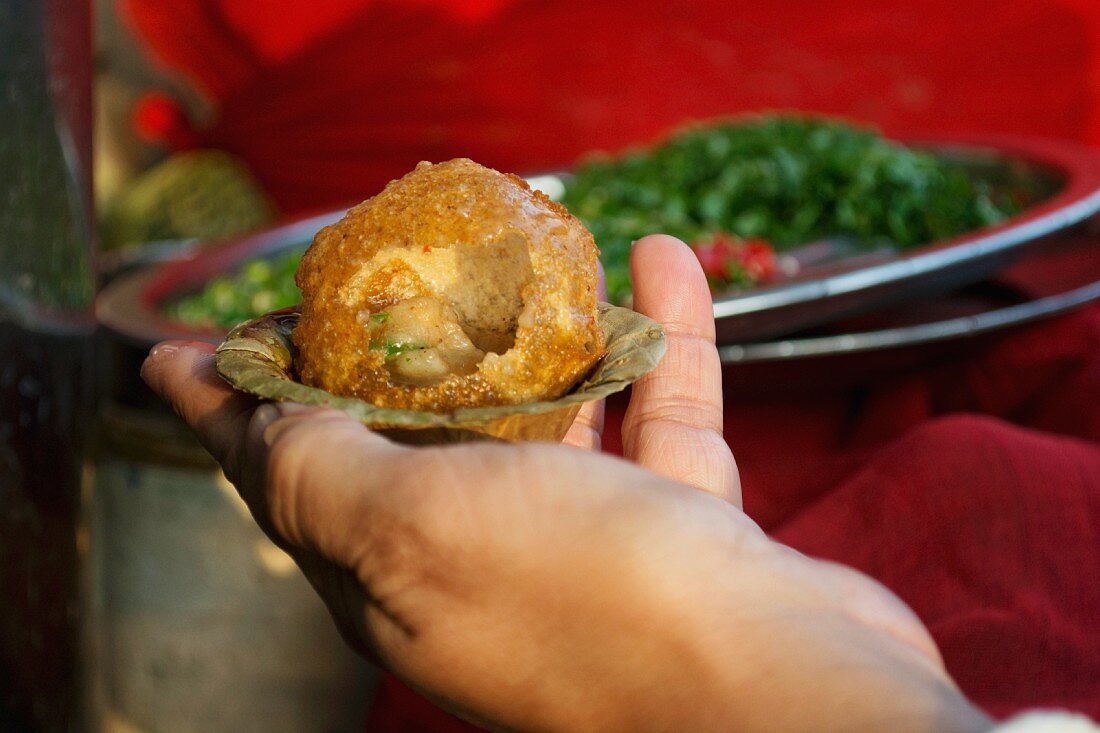 Indischer Mann mit Panipuri in einer kleinen Schale