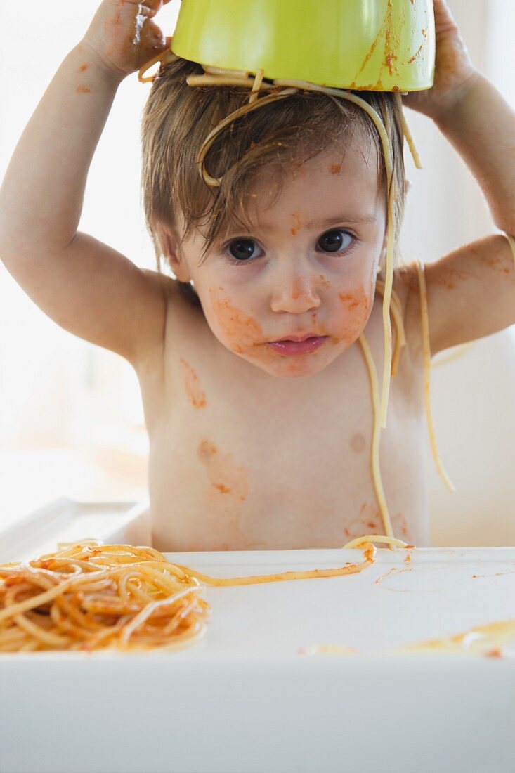 Girl eating spaghetti with tomato sauce