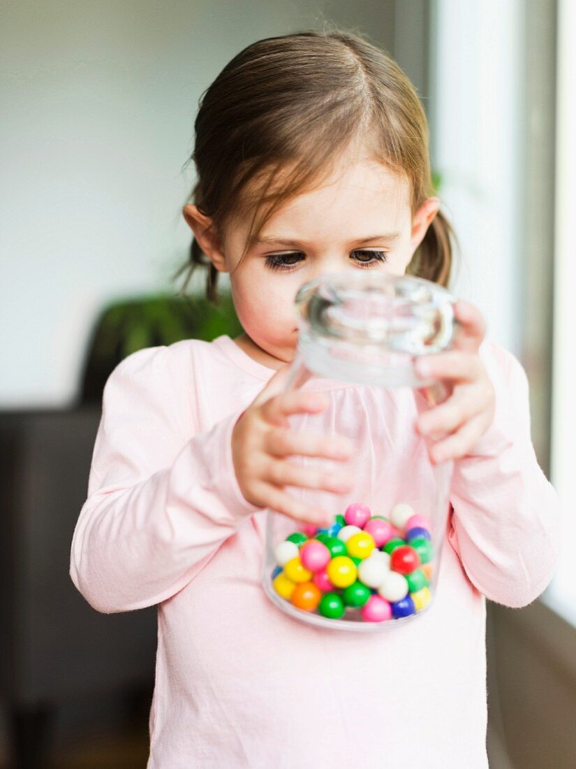 A little girl holding a jar of sweets