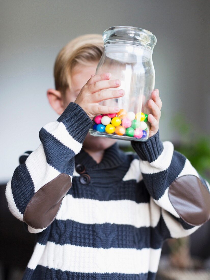 Junge hält Glas mit Bonbons