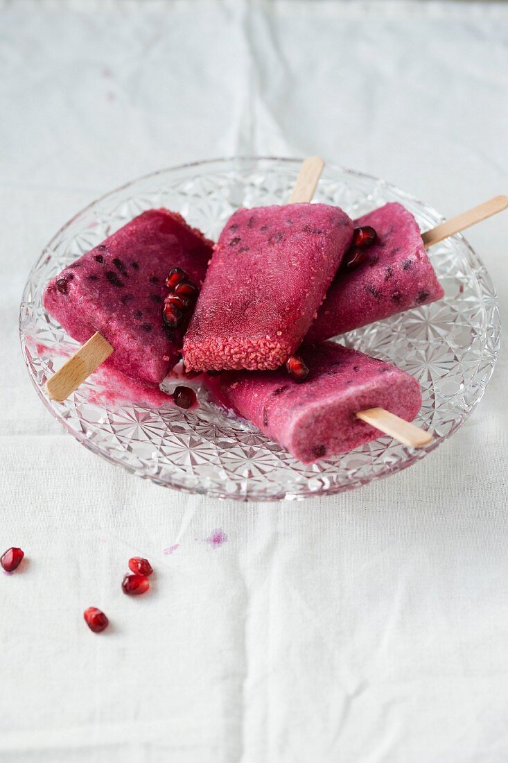 Four pomegranate ice lollies in a crystal bowl