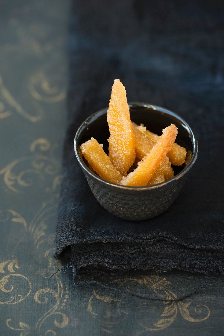 Candied ginger slices in a bowl on a black cloth