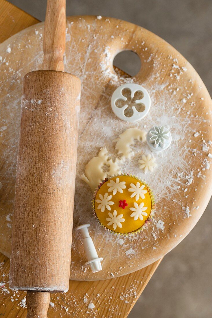 Cupcakes with marzipan fondant surrounded by baking utensils (seen from above)