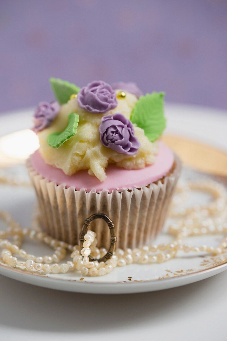 A cupcake decorated with rose petal fondant, buttercream and sugar roses