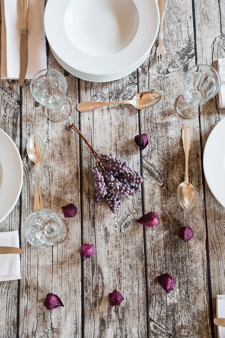 An autumnal laid table with wine glasses and purple flowers (seen from above)