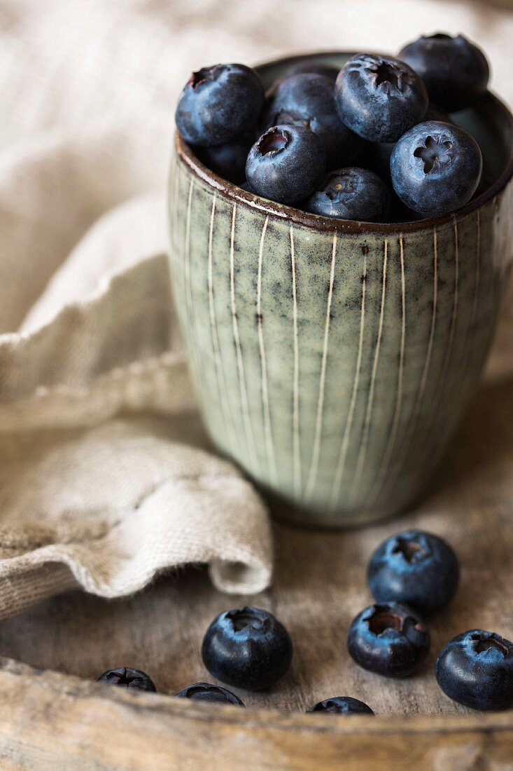 Blueberries in a cup on a wooden tray with a napkin