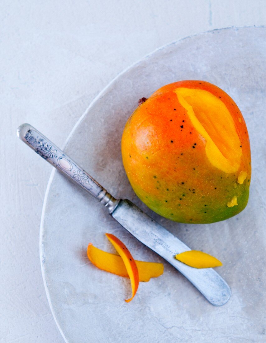 A mango, sliced, on a marble plate