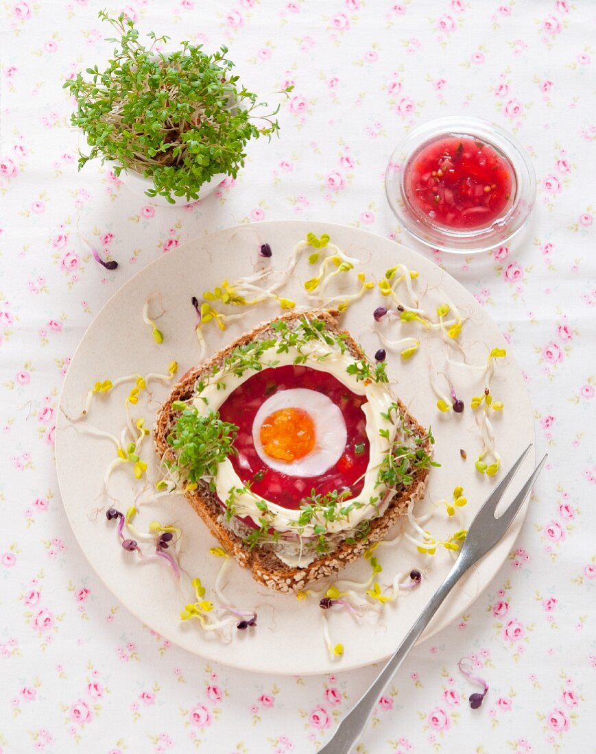 A slice of wholemeal bread topped with beetroot aspic, egg, mayonnaise, cress and radish sprouts