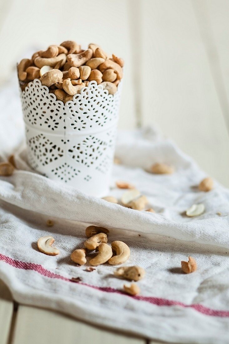 A cup of roasted, salted cashew nuts on a tea towel