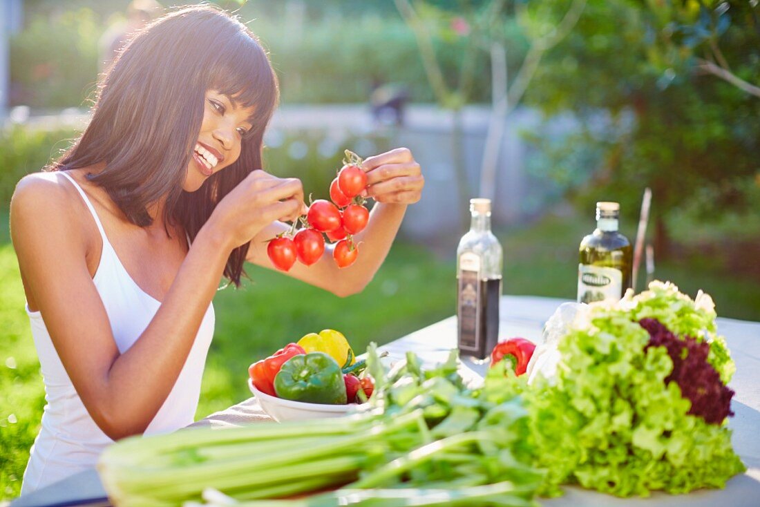 Junge Frau bereitet Gemüse auf dem Gartentisch vor