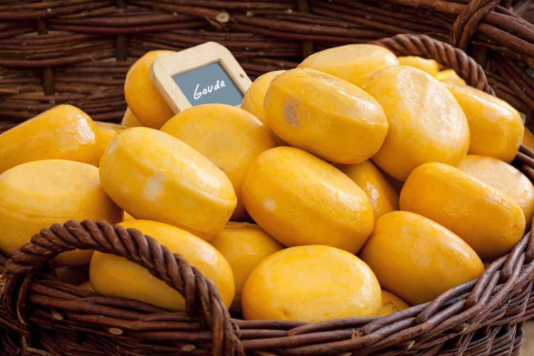 Mini wheels of Gouda cheese in a basket at a market