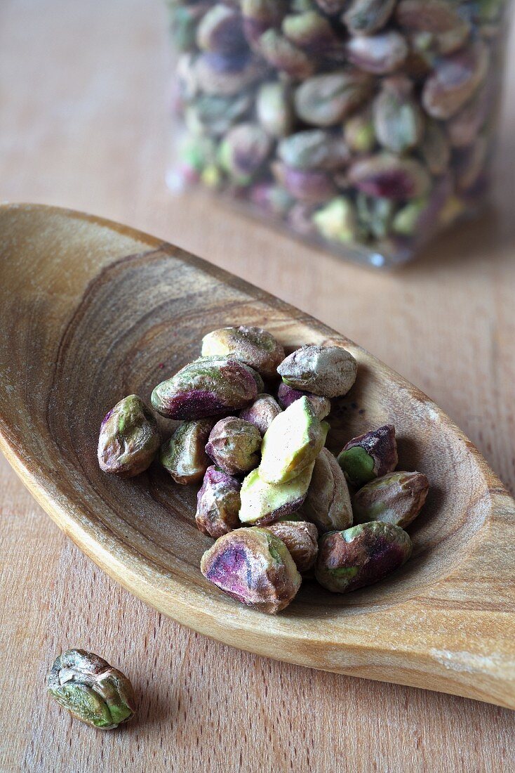 Shelled pistachios on an olive wood spoon
