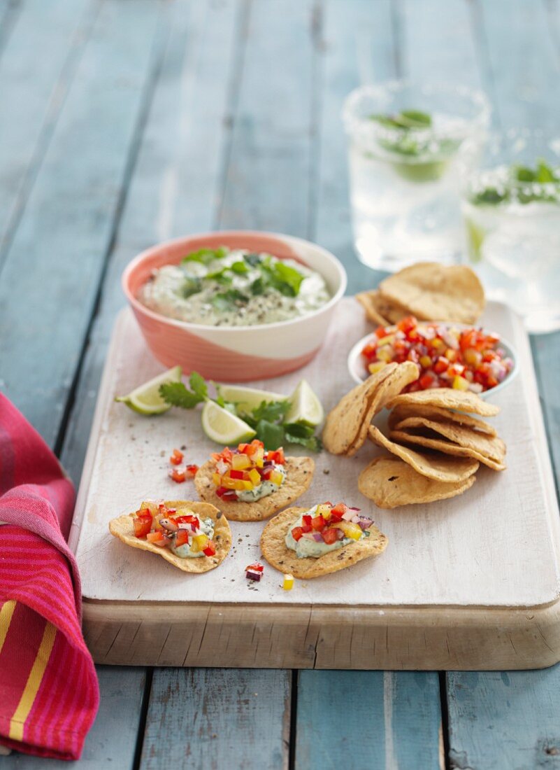 An avocado dip with corn crackers and vegetable salsa