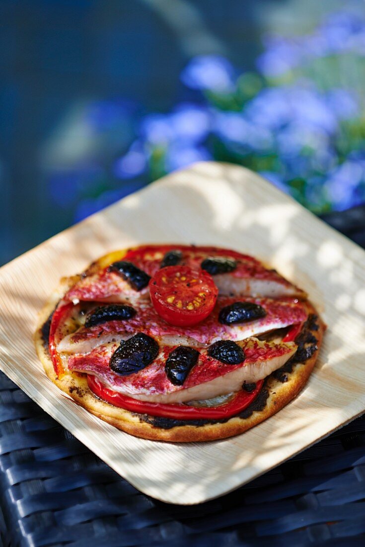 Pizza mit Rotbarben, Oliven und Tomate