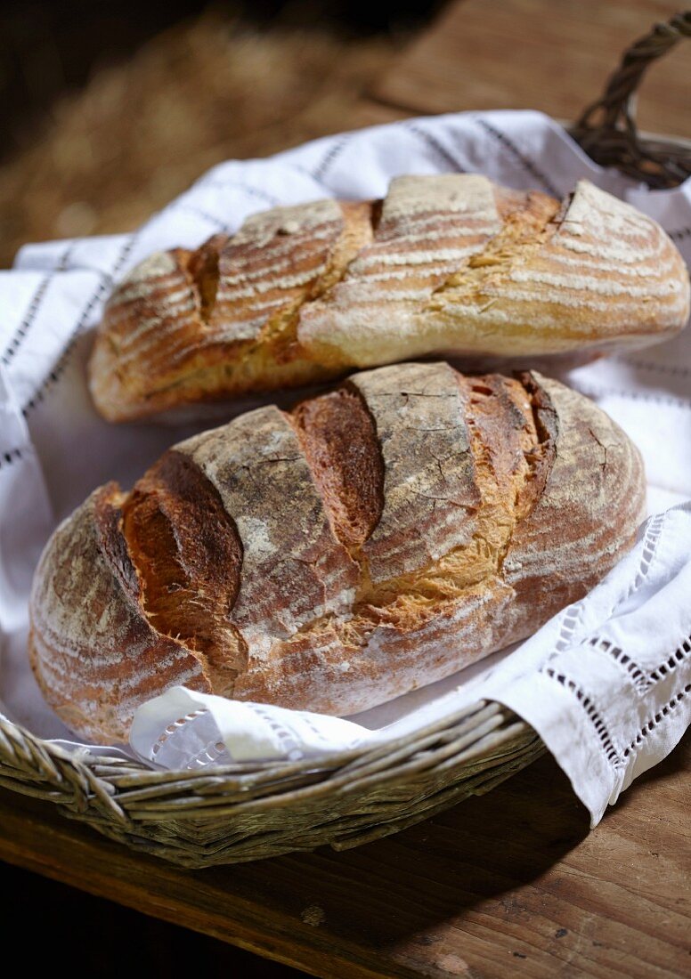 Zwei rustikale Brote im Brotkorb auf Holztisch